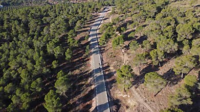Aerial drone shot of group of road cyclists ride along a mountain serpentine in Europe.