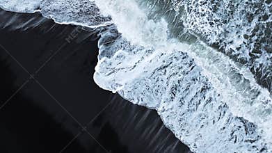 Aerial view of black sand volcanic beach with crashing waves, Serene and tranquil landscape. Famous landmark of Iceland.