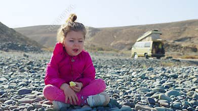Sad little girl sits alone away from the camper. Lonely childhood, homeless, or traveling