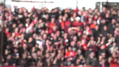 Many fans supporting soccer team at stadium. Blurred crowd of people at football stadium.