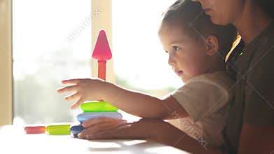 baby baby with mom collects a toy pyramid. happy family kindergarten kid dream concept. mom helps baby son collect a toy