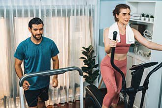 Athletic and sporty couple running on elliptical running machine at gaiety home.