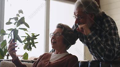 Happy elderly couple using smart phones together. Smiling senior couple using cellphones. Elderly couple using a smart