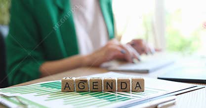 Agenda word on cubes and businesswoman is working on computer