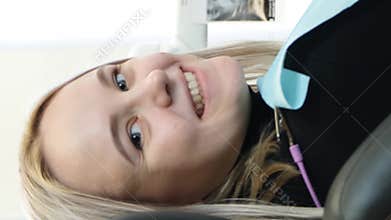 A woman in a dental chair with layered hair and blond bangs