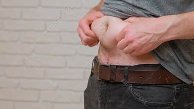Man demonstrates weight gain and health issues by pinching his belly fat to show effects
