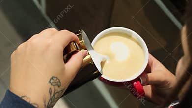 Barista pours frothed milk into coffee base closeup