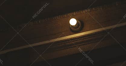 Old light bulb glowing in dark hallway closeup