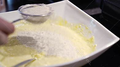 A woman&#x27;s hand mixes the dough with the added flour with a spoon.