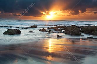 Sunrise landscape of ocean with waves clouds and rocks