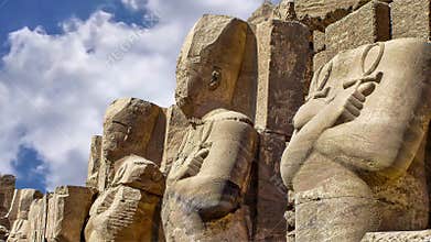 Row of carved statues with blue sky at Karnak Temple, Luxor