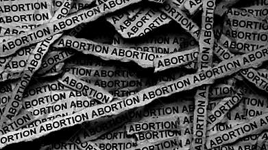 Strips of newspaper with the words Abortion typed on them. Black and white.