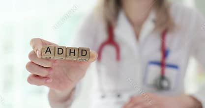 Doctor holds wooden cubes with word ADHD in hands in clinic