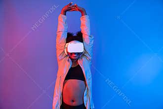 Young African sport woman wearing VR stretching whole body posing. Contrivance.