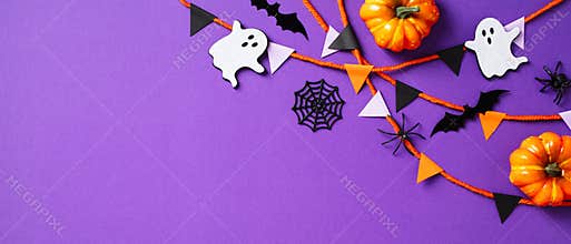 Halloween banner design. Flat lay pumpkins, spiders, ghosts, webs, bunting garland on purple background