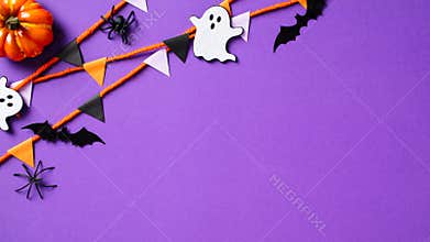 Happy Halloween concept. Halloween party decorations, pumpkins, ghost, bats, spiders, and bunting flag garland on purple