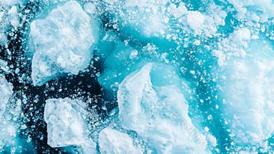 Aerial view of icebergs of different sizes and shapes floating in blue ocean water with smaller pieces of ice between