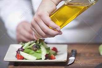 Chef Pouring Olive Oil Over Salad