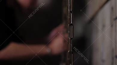 A close-up of a guy moving chains with weights up and down. Quest room.