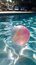 A colorful inflatable ball floating in a sparkling pool on a sunny day