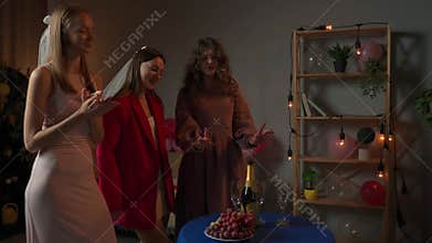 Group of young women friends and bride celebrating bachelorette party at home, bridesmaids preparing party snacks