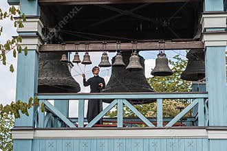 A person playing large bells from a balcony or tower, captured in motion with dynamic blur effects The old wooden