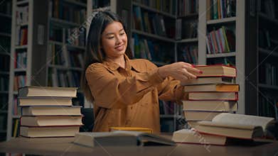 Asian woman girl student female library employee teacher bookworm reader sort books at desk near bookshelf preparing for