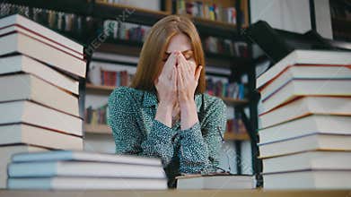 young red-haired woman student or businesswoman tired of reading books in the library for a long time. Female was tired