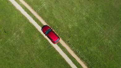 A car drives through the ruts of a dusty dirt road across wild deserts fields.