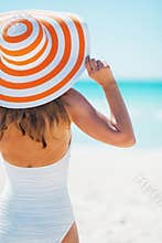 Young woman in swimsuit beach hat looking into distance