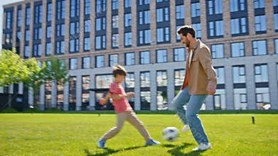 Father son playing football on grass near house. Happy family kid single parent