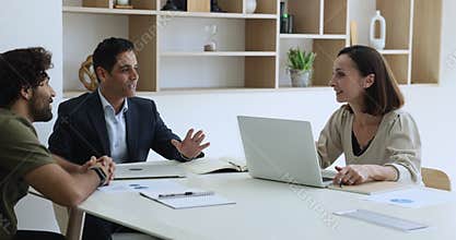 Confident positive Indian boss man talking to two diverse employees