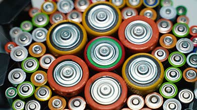 Different battery types rotate in a circle. Old used batteries