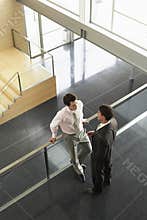 Businessmen Conversing By Railing In Office