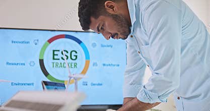 Asian Indian man work on laptop computer, businesspeople in team brainstorm meeting, ESG topic presentation on monitor