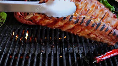 Chef turns over pork ribs On Grill. Cooking natural sausage on grill. Slow motion.