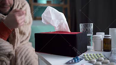 Flu illness concept. Sick man uses paper tissues during sickness attacks