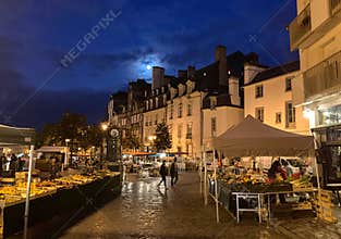 Vendors set up in early morning under a full moon for the Saturday Lices Market in Rennes, Brittany, France.