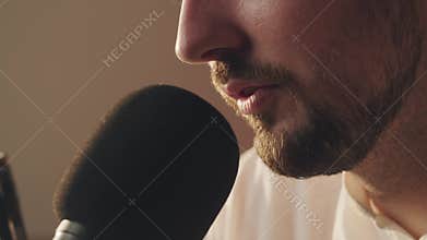 Podcast recording. Close up shot bearded guy saying to microphone in his private audio studio. Professional musician