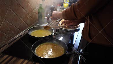 Cook prepares orange sauce for pancakes in pans on the stove