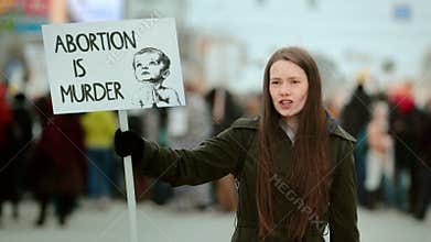 Anti murder demonstration city street. Stop abortion protest. Girl hold placard.