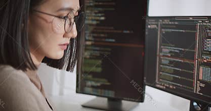 Asian female software developer coding program on desktop computer. Woman work from home