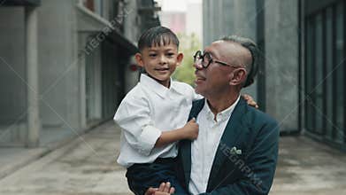 Man dressed in jacket holds small son tightly in arms