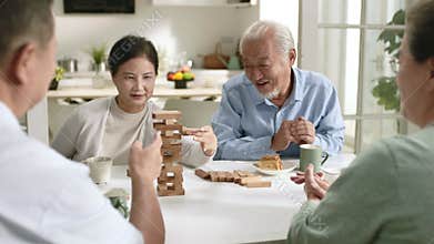 two senior asian couples enjoying playing with building blocks