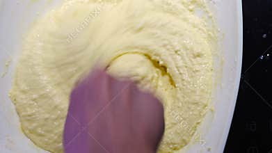 A woman&#x27;s hand mixes the dough with the added flour with a spoon.