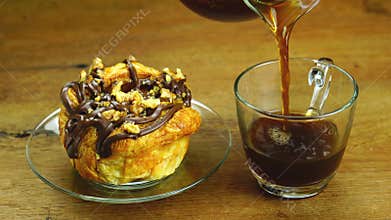 High angle view of pouring hot black coffee into transparent glass cup.