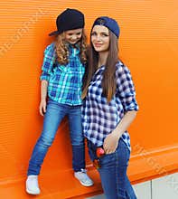 Stylish mother and child daughter together, happy mom with kid girl in casual clothing in the city