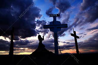 Woman Praying at Cross in Sunset