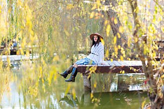 Autumn lake woman. She sits by a pond on a wooden pier in autumn and admires nature. The concept of tourism, weekends