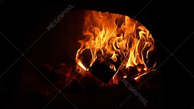 Fire warms surroundings. Crackling flames cast inviting glow